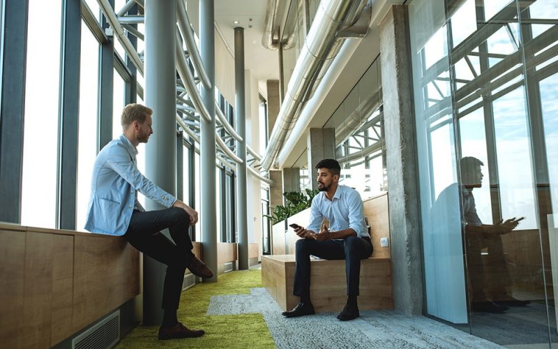 Two colleagues having a casual chat in the office lobby.